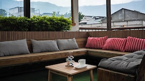 A corner seating area with a wooden bench, cushions, and a small table with a cup and saucer. - CASA DARA, with a view of the Mayan Face Mountain and Lake Atitlán! (San Juan La Laguna)