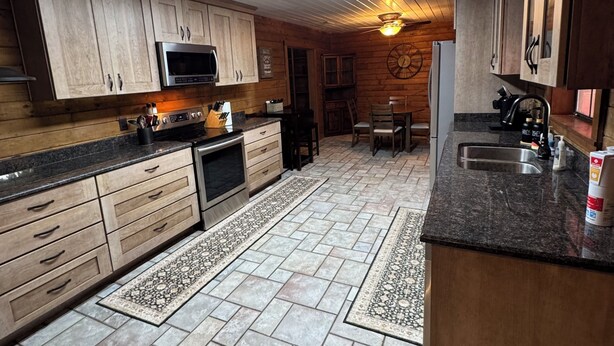 A kitchen with wooden cabinets, a microwave, a stove, and a dining area with chairs and a table.
