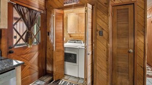 A laundry room with a washing machine, a door labeled 'LAUNDRY,' and a wooden interior.