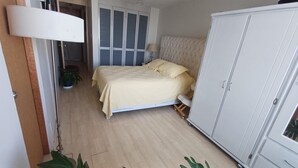 Ein Schlafzimmer mit einem Bett, einem Kleiderschrank, einer Lampe und einem Blumentopf.