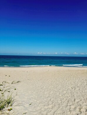 Uma praia com céu claro e ondas oceânicas calmas.