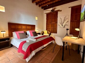 Un dormitorio con cama, mesitas de noche, escritorio y silla.