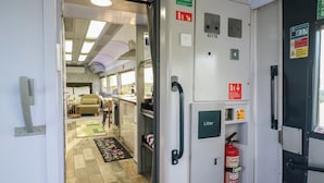 A compact kitchen with a refrigerator, a coffee machine, and a fire extinguisher. - The Carriage Ely Penzance (Ely)