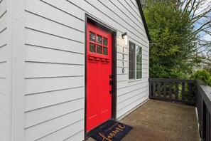 A white house with a red door, a black mailbox, and a number '130' on the wall.