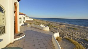 A seaside walkway leading to a beach, with a building featuring a tiled floor and a door. - Charming and Rustic Beachfront Home Sun House (Puerto Peñasco)