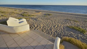A beach with a tiled walkway leading to a white structure, a sandy beach, and the ocean in the background. - Charming and Rustic Beachfront Home Sun House (Puerto Peñasco)
