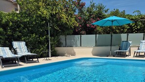 Una piscina limpia con sillas de descanso y una sombrilla.