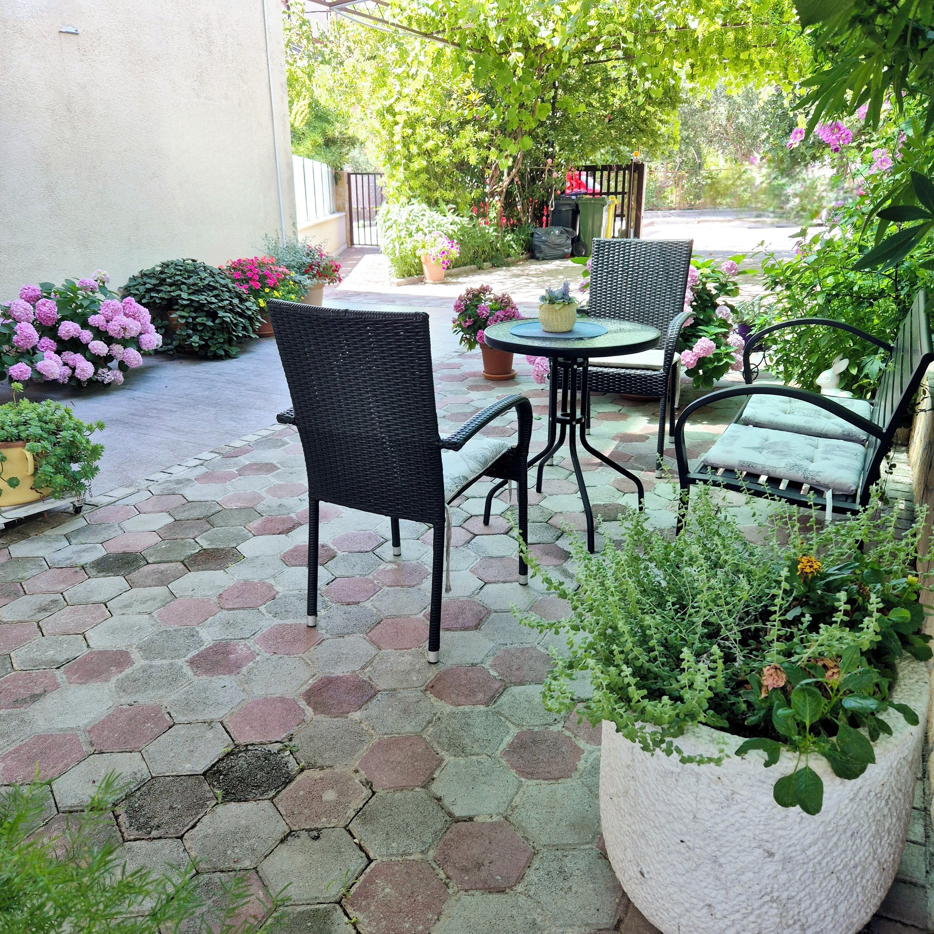 Une terrasse avec des carreaux hexagonaux, des meubles en osier et des plantes en pot.