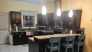 A kitchen with a central island, dark cabinets, and pendant lighting. - Cozy 2-bedroom house where you can "Relax, Recharge, Repeat" (Bodden Town)