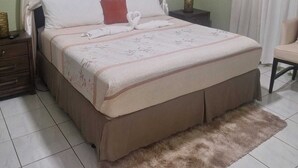 A bedroom with a bed, curtains, a nightstand, a chair, and a decorative wall piece. - Cozy 2-bedroom house where you can "Relax, Recharge, Repeat" (Bodden Town)