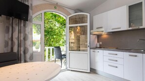 Een moderne keuken met witte kastjes, een inbouwoven en een groot raam met uitzicht op groen.