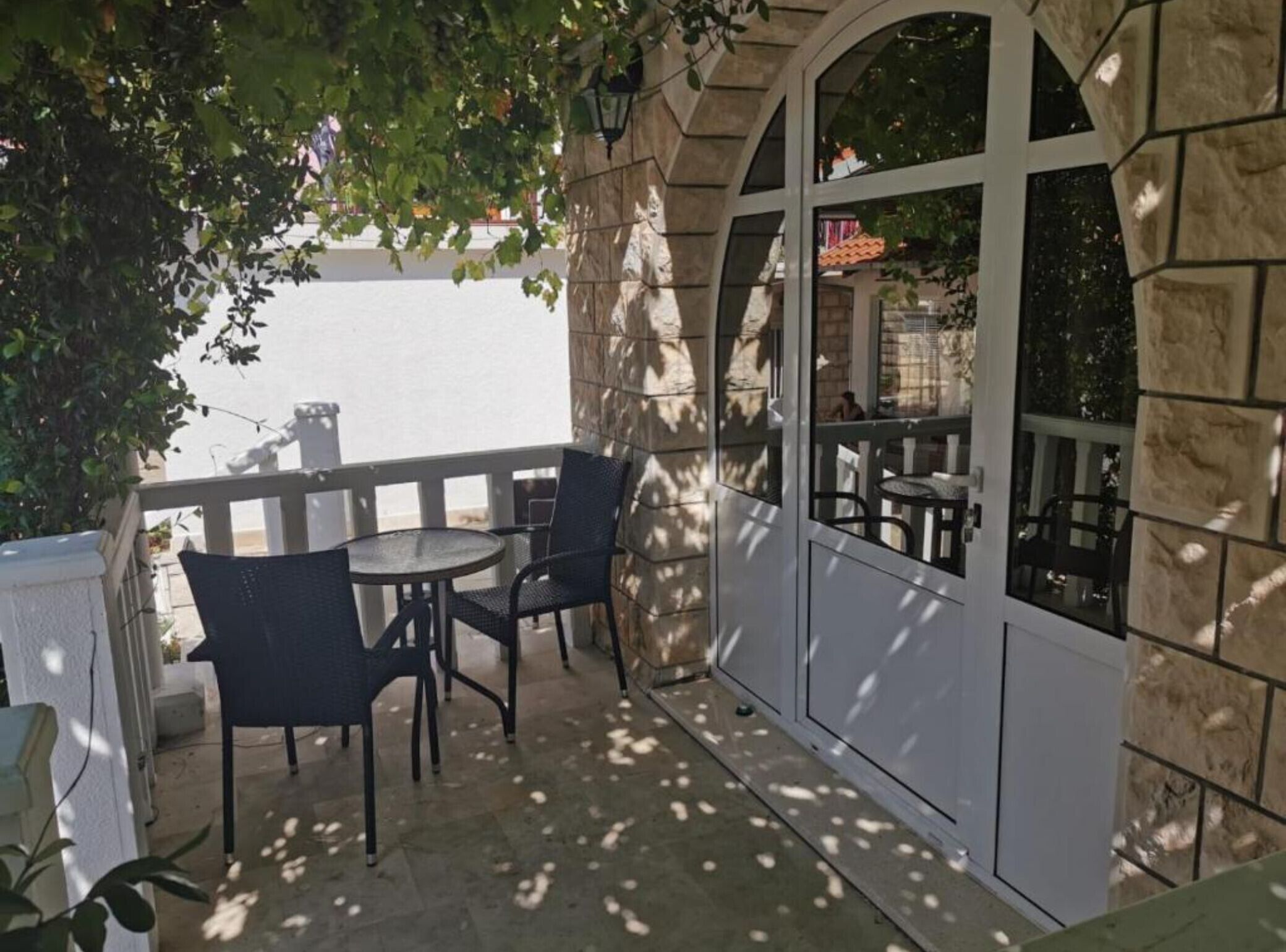 Un patio con una mesa y sillas, un muro de piedra y vista a la calle.