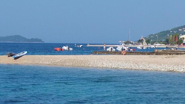 A coastal scene with boats, a beach, and a distant hill. - Adriatic Guesthouse Balota with Shared Pool- Bungalow with Terrace (1) (Viganj)