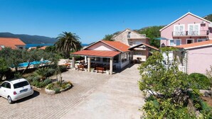 A coastal property with a covered patio, a swimming pool, and a car parked in the driveway. - Adriatic Guesthouse Balota with Shared Pool- Bungalow with Terrace (1) (Viganj)