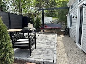 Un patio con mobiliario exterior, una hamaca y una casa al fondo.