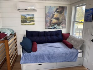 A cozy room with a bed, a window, and artwork on the walls.