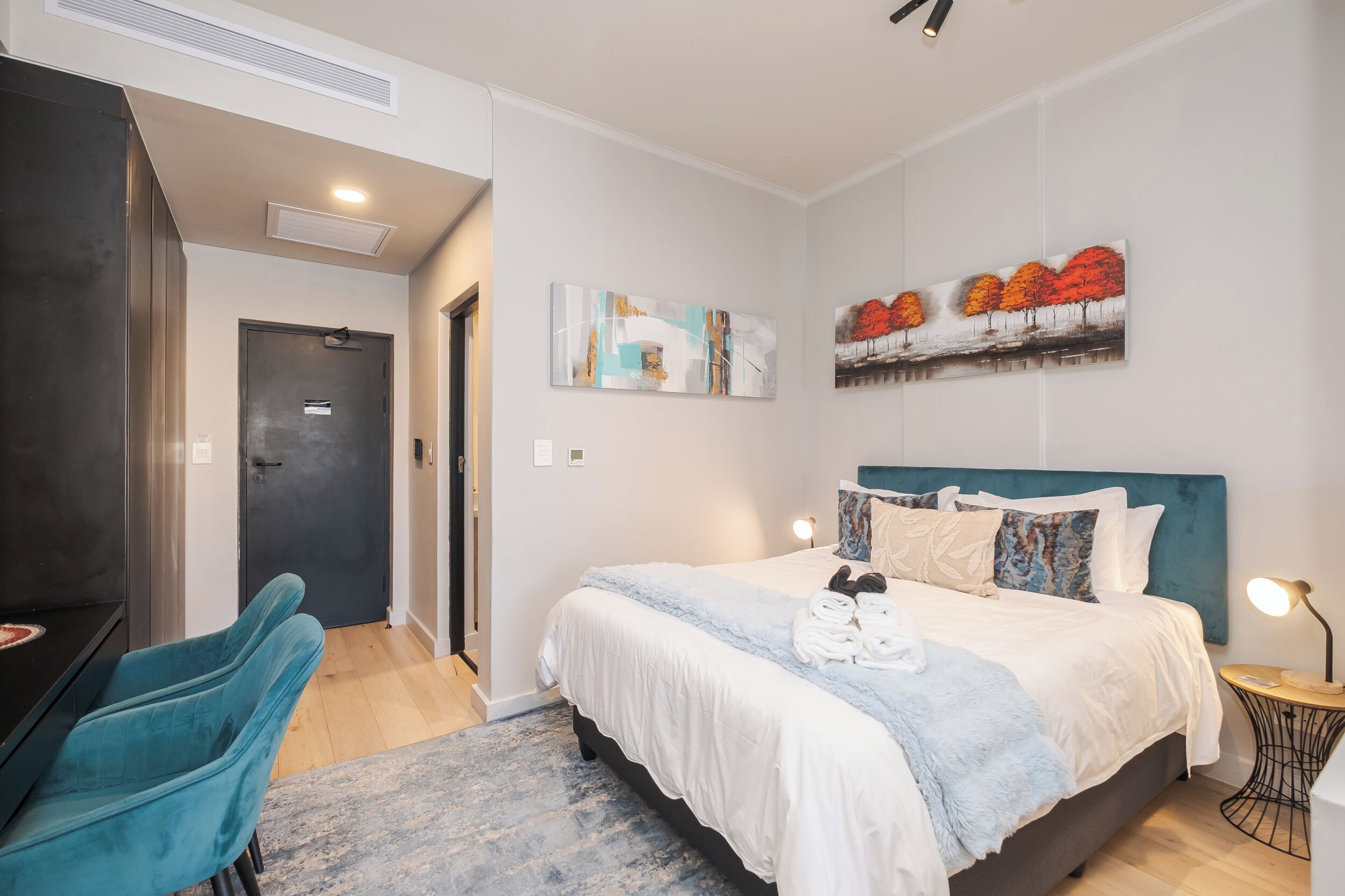 A bedroom with a bed, a desk, and a chair.