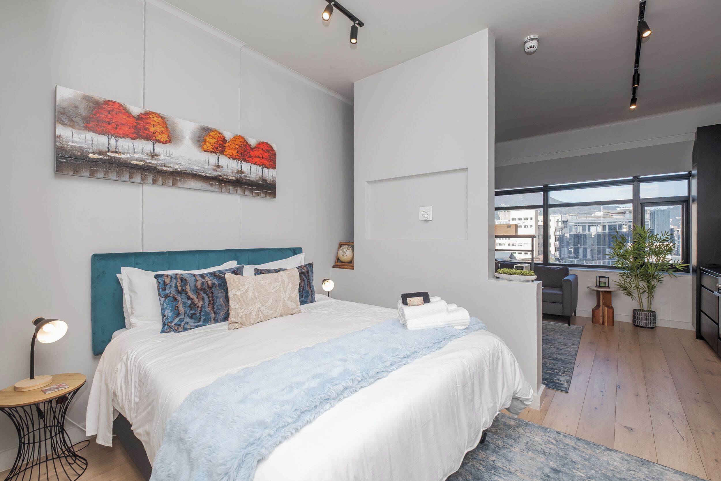 Une chambre d’hôtel moderne dotée d’un grand lit, offrant une vue sur la ville et comprenant un coin repas.