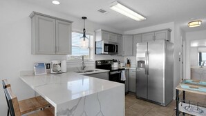 Una cocina moderna con armarios blancos, electrodomésticos de acero inoxidable y una isla de mármol.