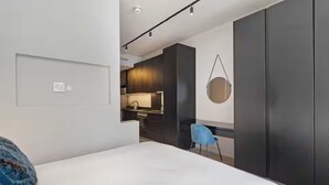 Une chambre moderne équipée d’un lit, d’un bureau et d’une kitchenette.
