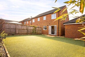 A residential property with a fenced backyard, a brick house, and a door leading to a covered porch. - Stylish 3BR Retreat w/ 6 Beds, Sleeps 7, Parking (Greater Manchester)