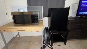 Eine kleine Küche mit Mikrowelle, Kühlschrank und einem Hängeschrank.