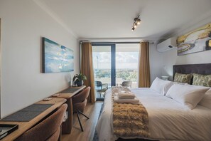 A hotel room with a bed, desk, chair, and a view through the window.