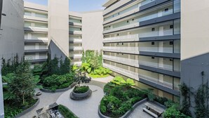 Un edificio a più piani con balconi, un cortile centrale con vegetazione e un design architettonico moderno.