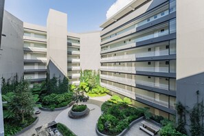 A multi-story building with balconies, a central courtyard with greenery, and a modern architectural design.