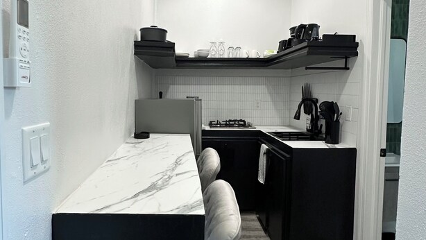 Una cucina compatta con un piano di lavoro in marmo, un piano cottura integrato e un'isola nera.