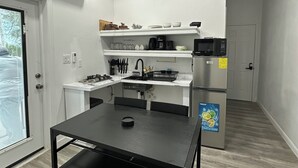 Una cucina moderna con mobili bianchi, un tavolo nero e un frigorifero in acciaio inossidabile.