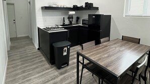 Una cucina moderna con isola centrale, mobili neri e zona pranzo con tavolo e sedie in legno.