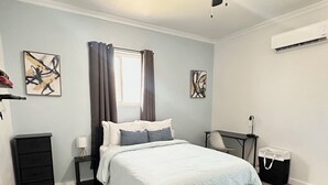 Una camera da letto moderna con un letto, comodini, una scrivania e un condizionatore d'aria.