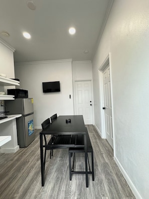 A modern kitchen with white walls, a black dining table, and a built-in microwave.