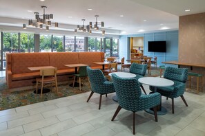 Un espace de détente moderne comprenant un canapé, des fauteuils, des tables et un téléviseur.