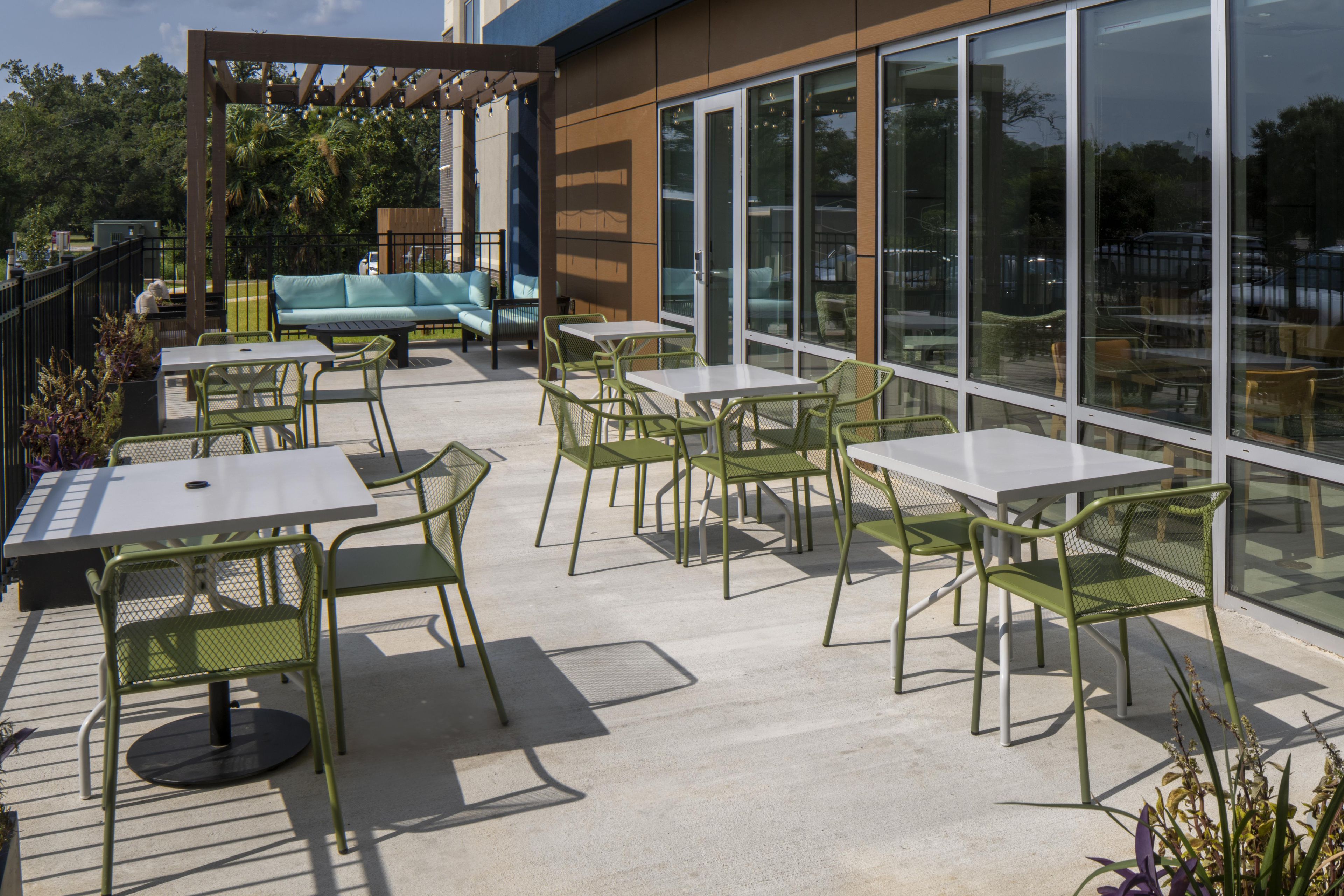An outdoor patio area with tables and chairs, a sofa, and a pergola with string lights.