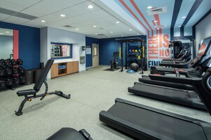 Un gimnasio con cintas de correr, máquinas de pesas y pesas libres.