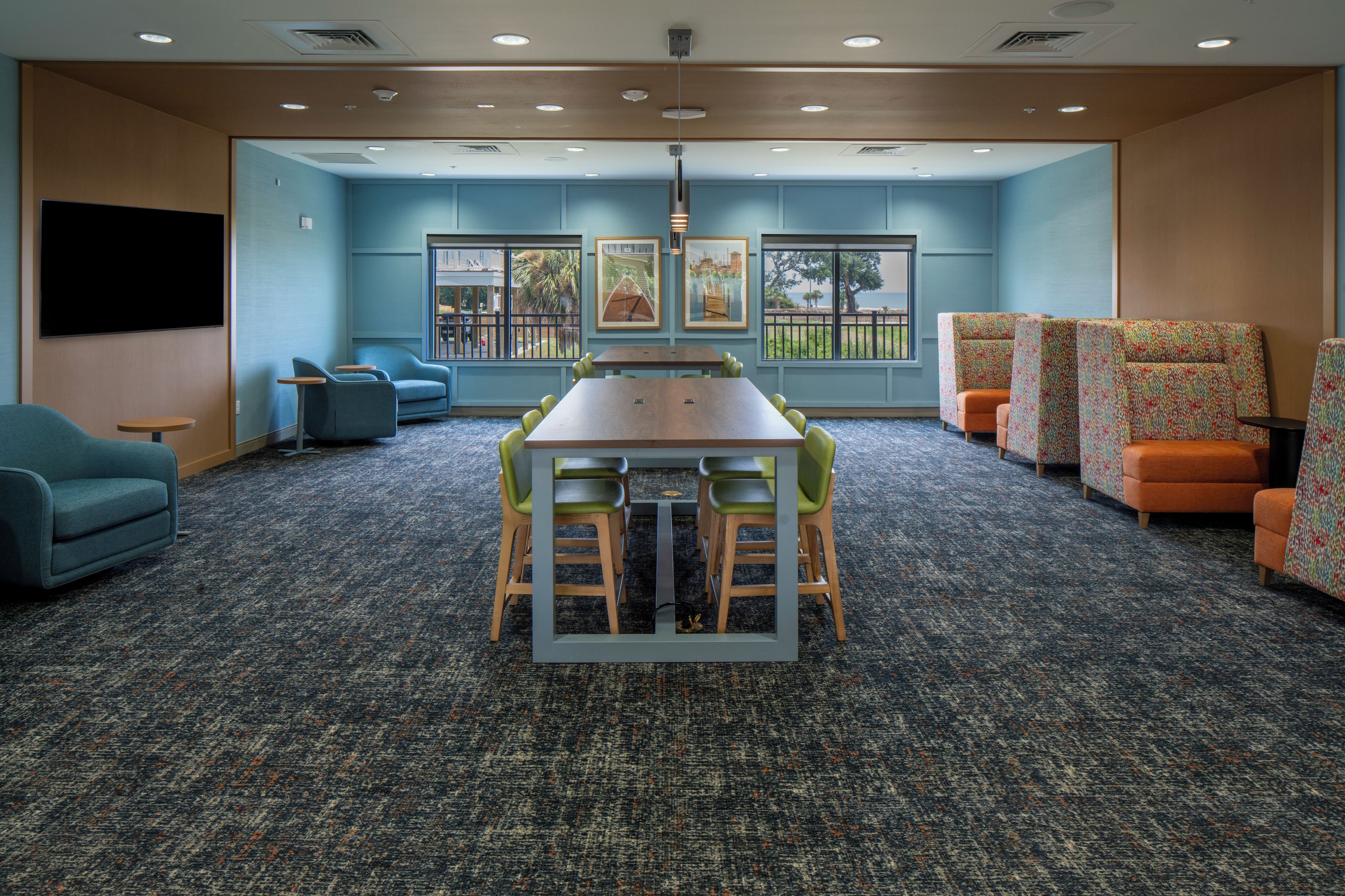 A conference room with a large table, chairs, and a view of the outdoors.