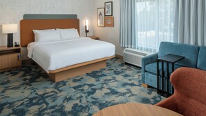 Hotellihuone, jossa on sänky, työpöytä, tuoli, lamppu ja ikkuna, jossa on verhot.