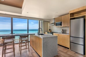 A modern kitchen with a large island, wooden cabinets, and a view of the ocean. - Hilton Club Ka Haku Honolulu (Honolulu)