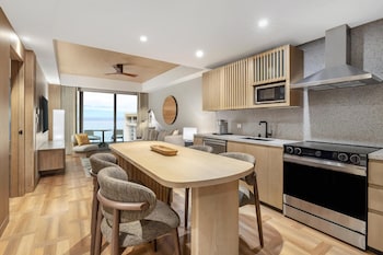 A modern bathroom with a wooden vanity, a large mirror, and a view of the outdoors. at Hilton Club Ka Haku Honolulu