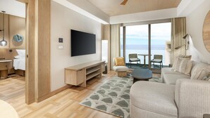 Ein modernes Hotelzimmer mit Holzboden, einem Flachbildfernseher, einer Couch, einem Couchtisch und Blick aufs Meer.