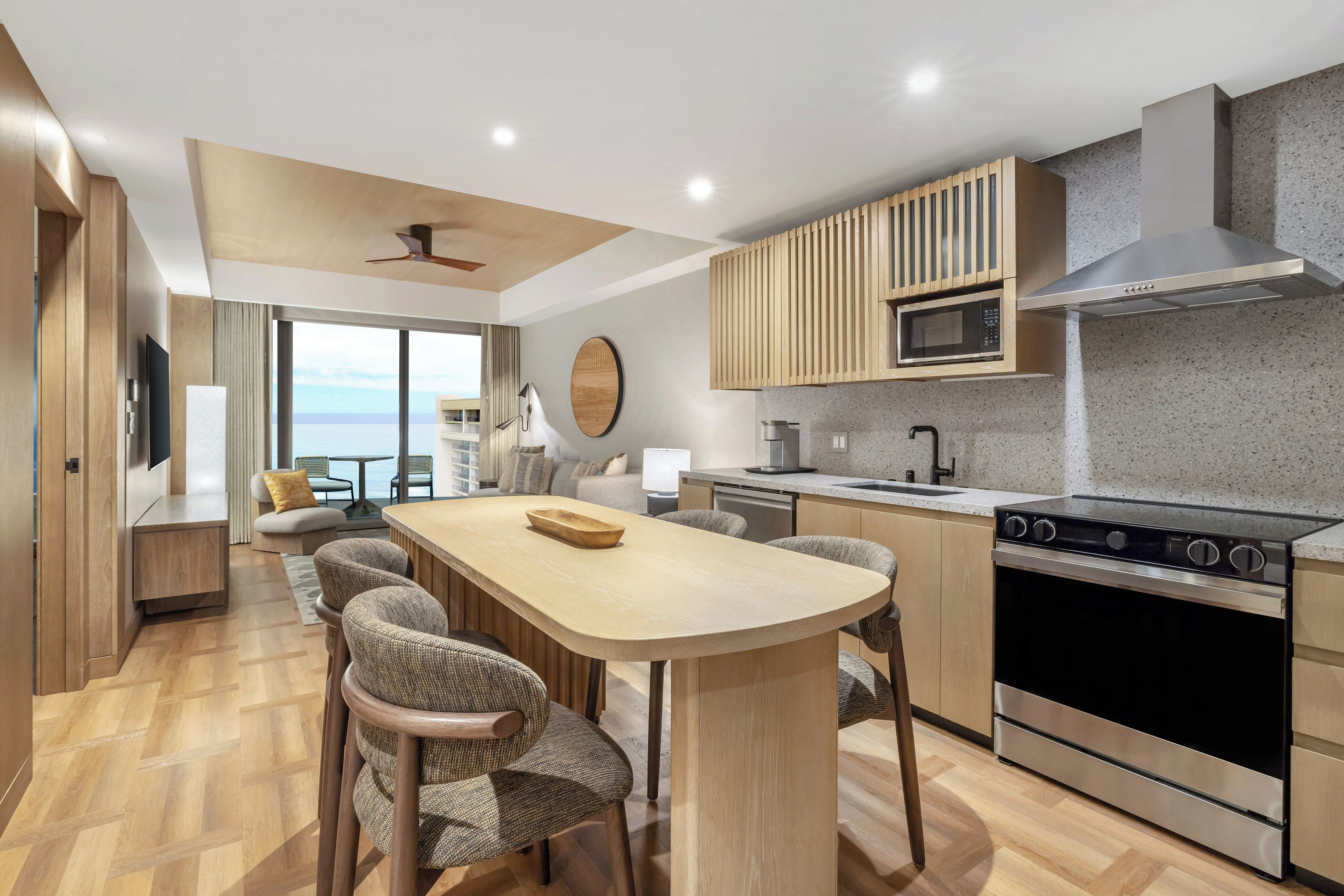 A modern kitchen with a central island, built-in appliances, and a view to the outside.