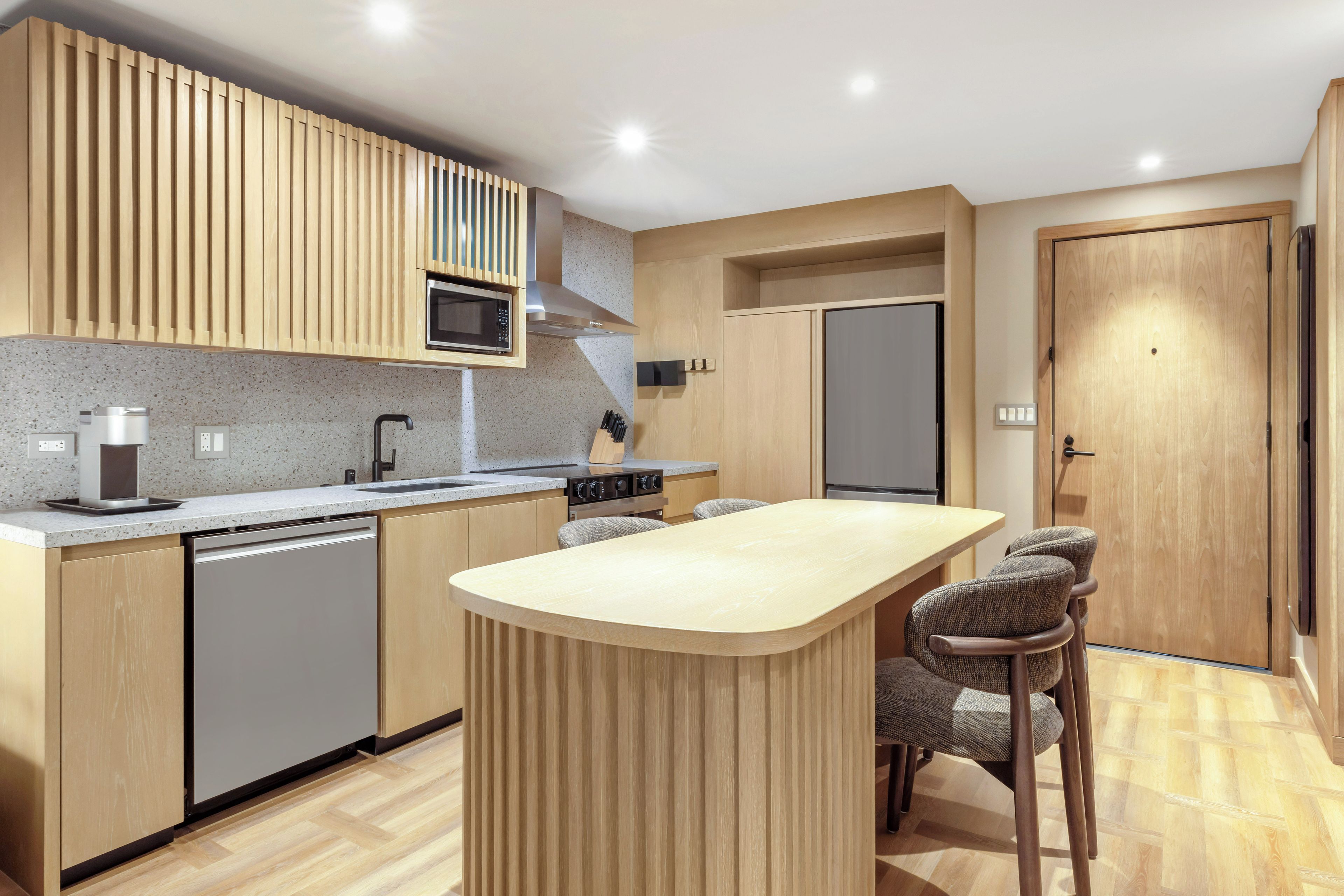 A modern kitchen with a central island, built-in appliances, and a wooden finish.