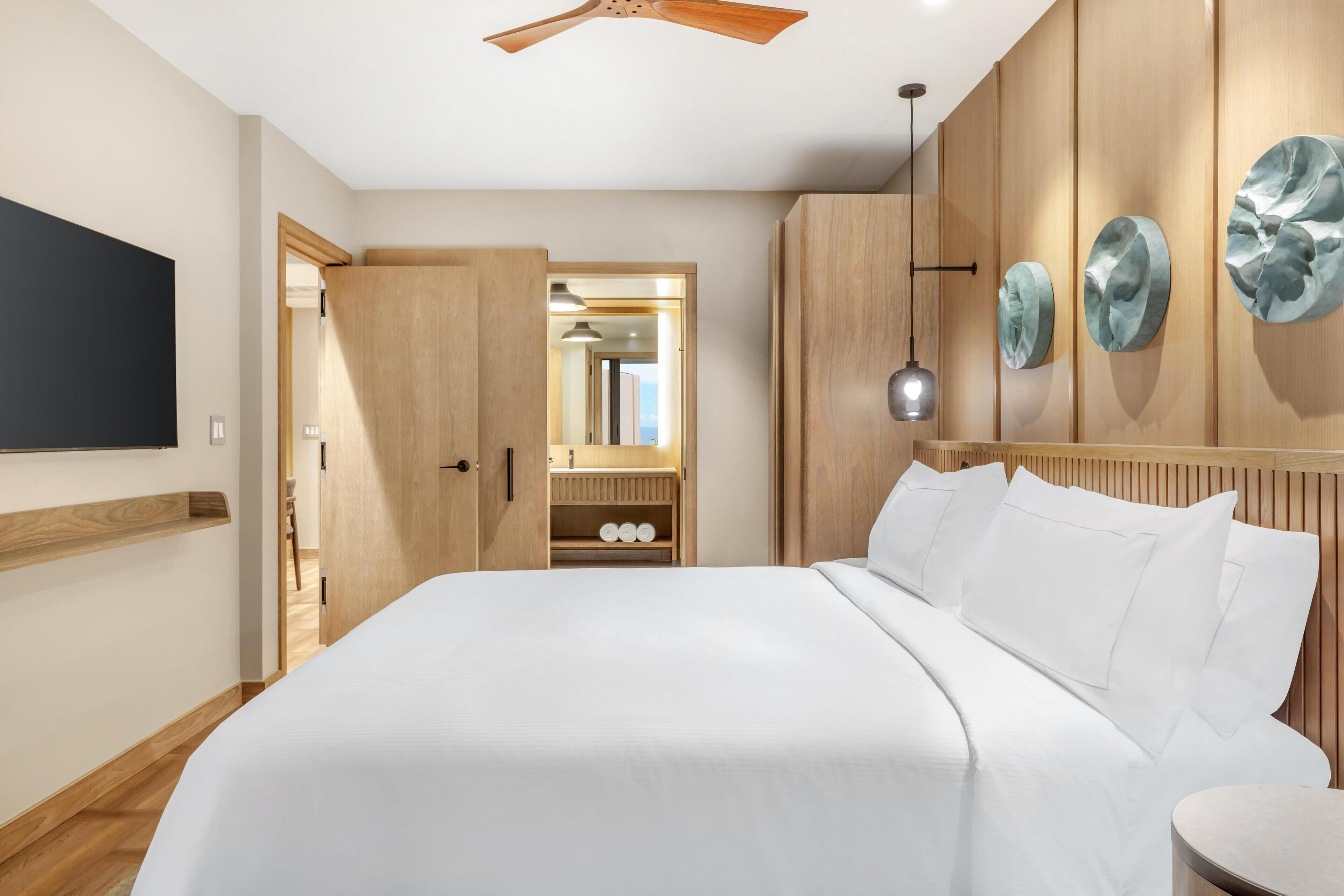 Een moderne slaapkamer met een bed, een houten garderobe en een plafondventilator.