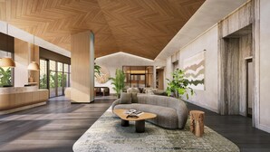 Ein modernes Interieur mit Holzboden, einer Rezeption, einer Sitzecke mit Sofa und Couchtisch sowie einem großen Fenster.