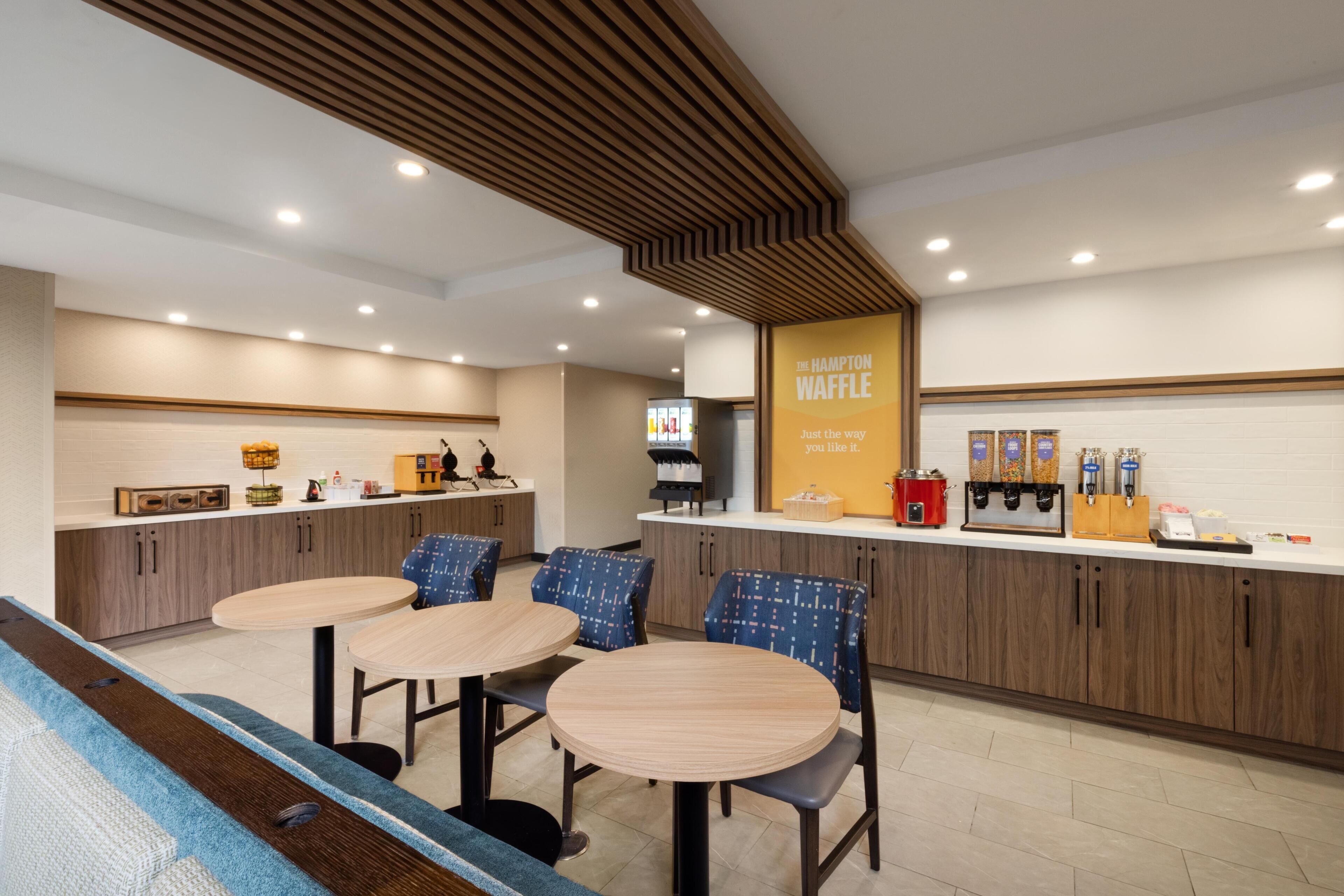 A modern kitchen area with a counter, seating, and a waffle station.