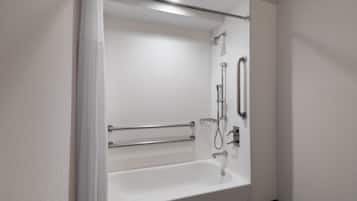A modern bathroom with a white bathtub, grab bars, a showerhead, and a handheld shower attachment.