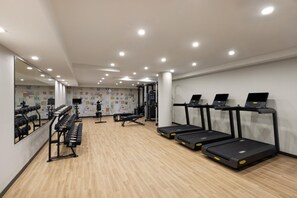 A gym with treadmills, dumbbells, and a mirrored wall. - Hampton Inn Long Island City  NY (Long Island City)