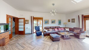 A spacious living room with a herringbone floor, a brown leather sofa, a blue armchair, and a glass coffee table. - Villa in Kavac with beautiful sea view (Kavač)